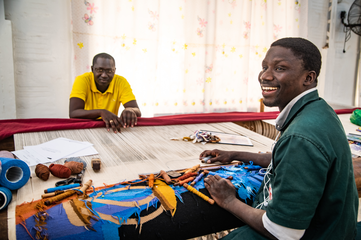 Skilled Senegalese weavers producing a handcrafted tapestry on traditional looms at the Manufacture Sénégalaise des Arts Décoratifs in Thiès.