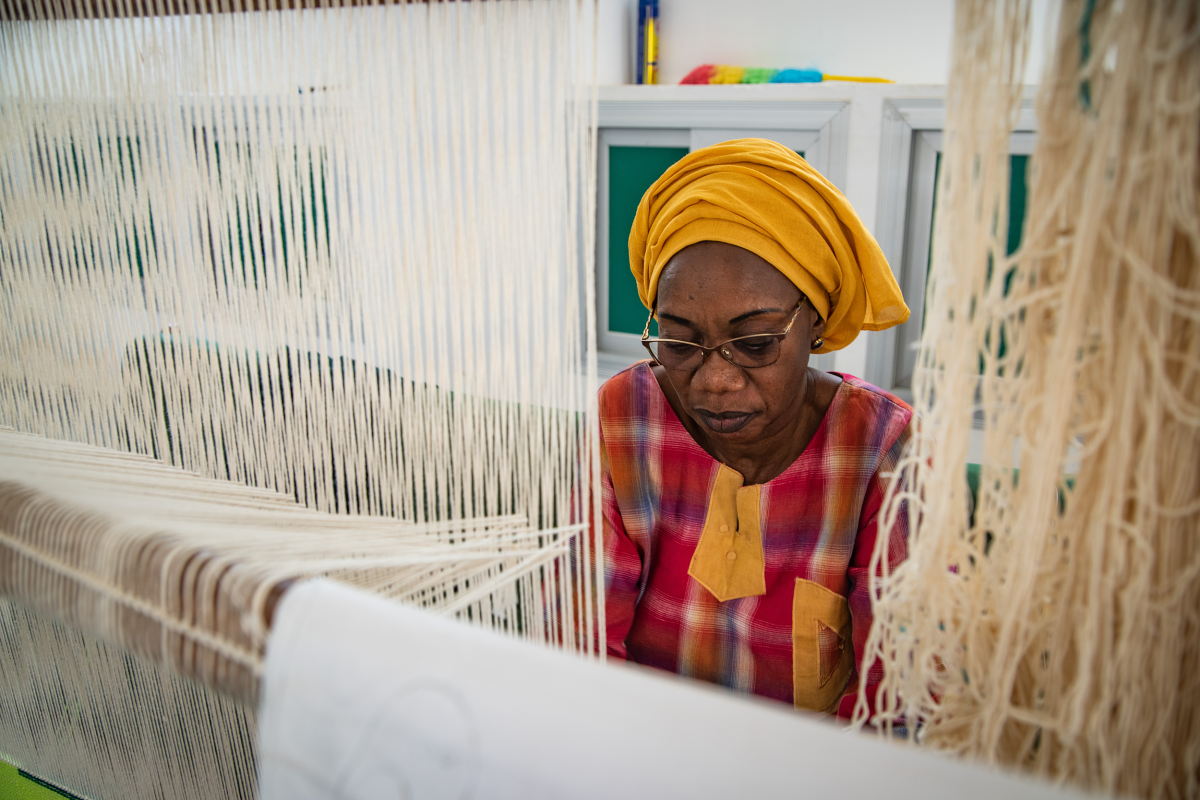 Close-up of an artisan weaving a colorful Senegalese tapestry at the Thiès tapestry workshop.